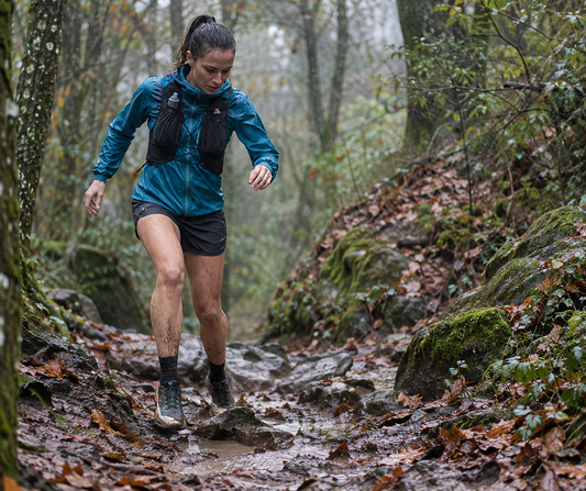 Corredora atravesando un sendero embarrado bajo la lluvia