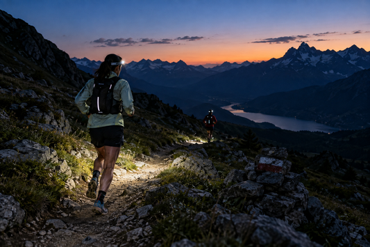 Dos corredores con frontal en un sendero de montaña al anochecer