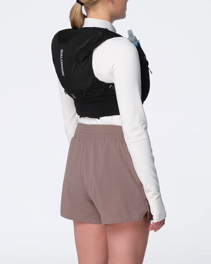 Chaleco de hidratación Salomon ADV Skin 12 para mujer negro puesto por una corredora, vista trasera de tres cuartos
